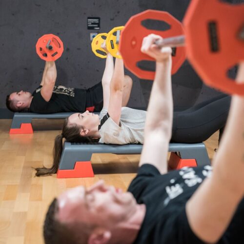 people doing bench presses in an exercise class