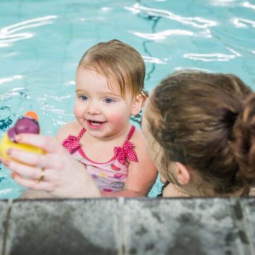 woman and child in the pool playing with little rubber ducks