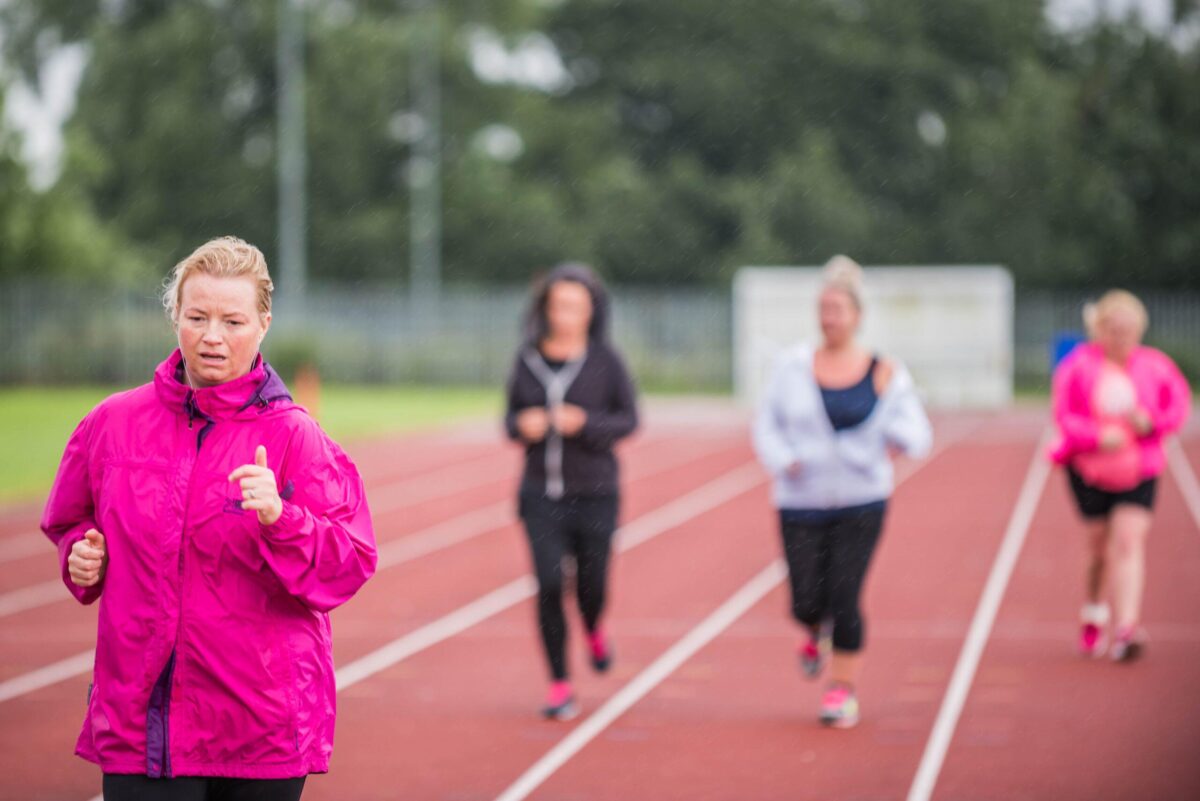 women running on the running track in coats