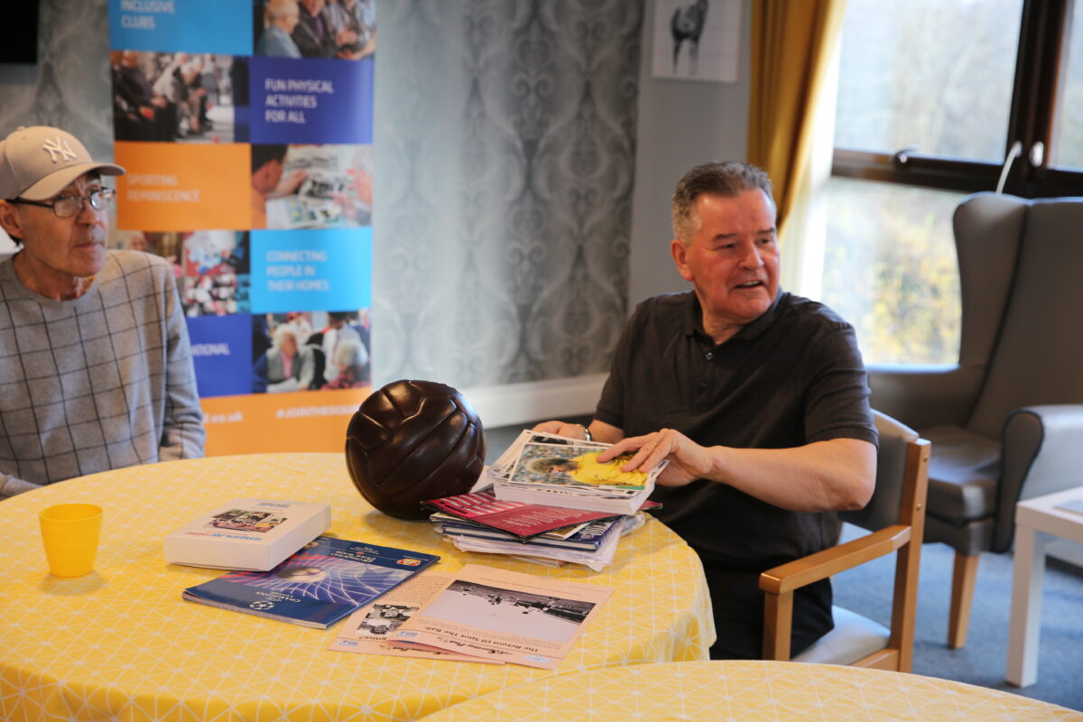 men sat at a table with a football and books