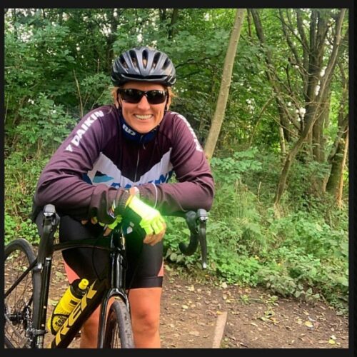 Stacey Copeland smiling over bike handlebars in woodland