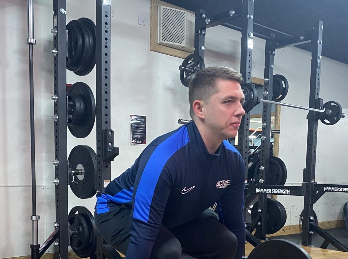 man squatting with bar weights