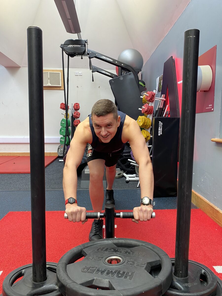 man pushing weights on sled